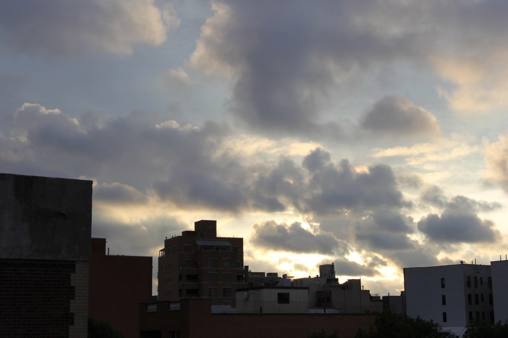 puffy clouds over queens rooftops at dawn