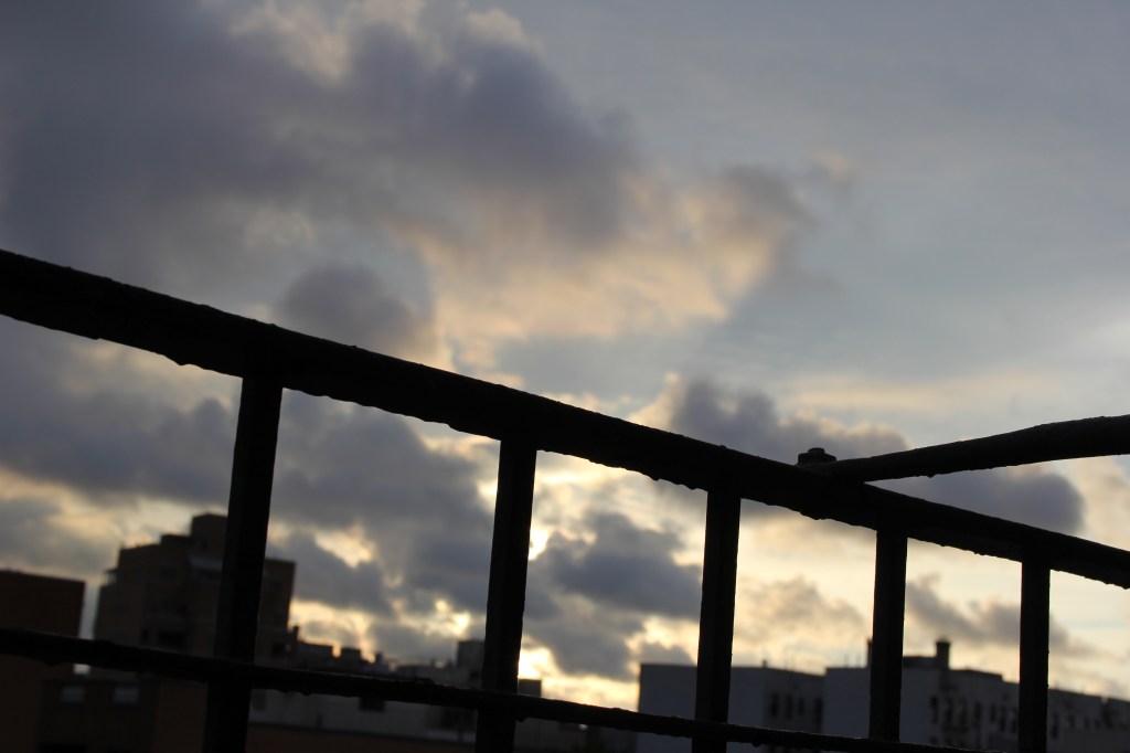early morning sunset in yellow and gray, seen through the bars of a fire escape